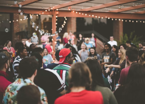 Crowd of people at an outdoor evening festival with string lights